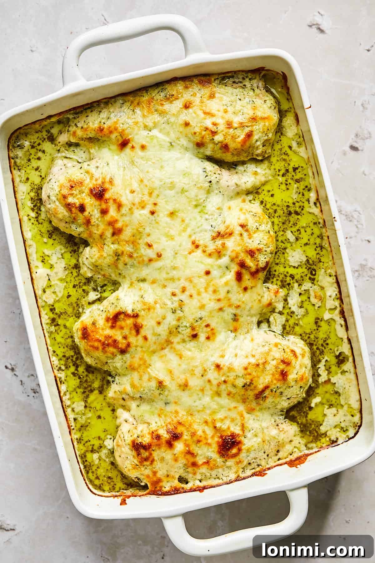 Baked pesto chicken with golden cheese topping and visible bubbling edges