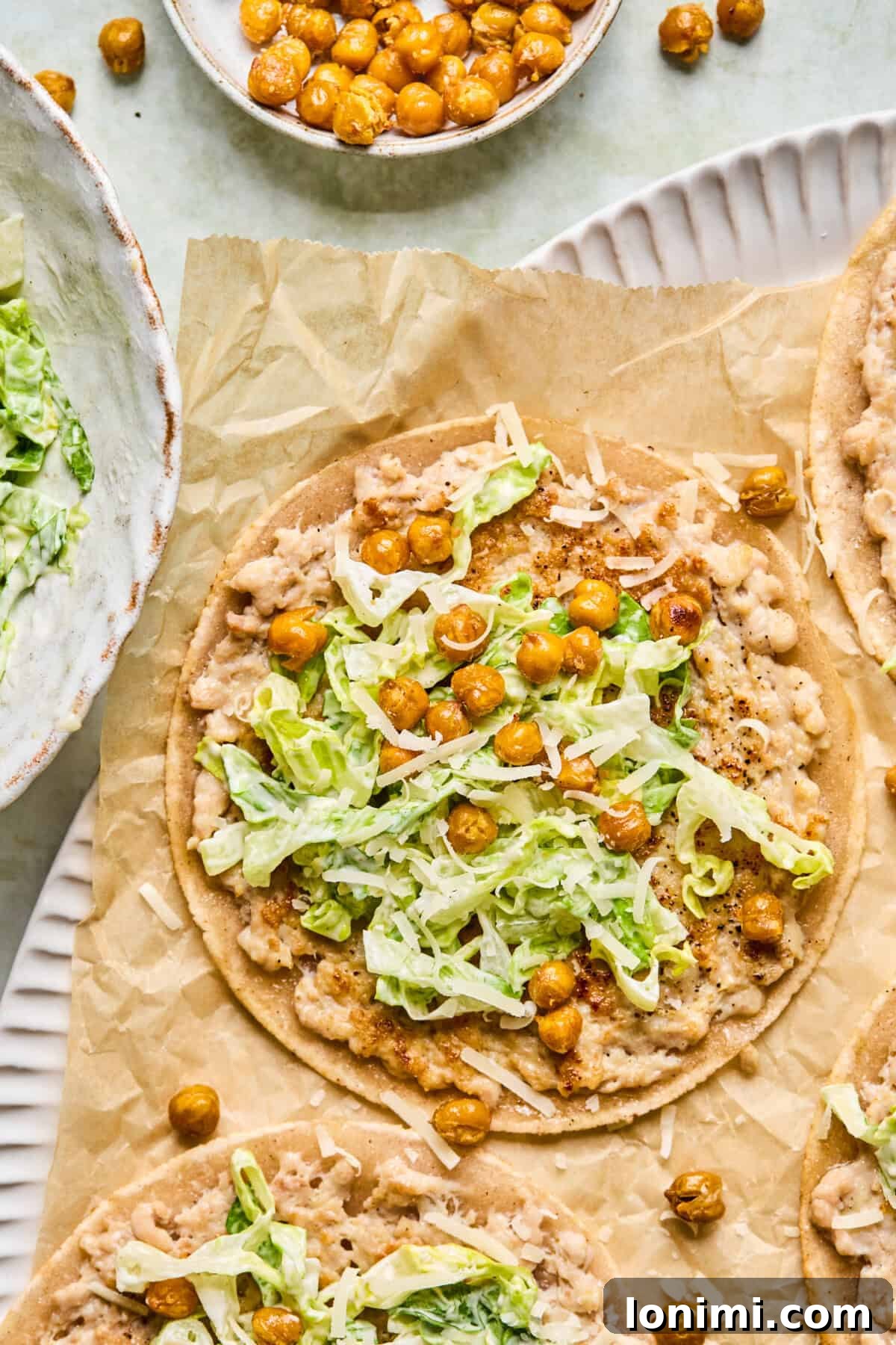 Step 8: Close-up of taco assembly with fresh romaine, shredded parmesan, and crispy chickpeas as toppings.