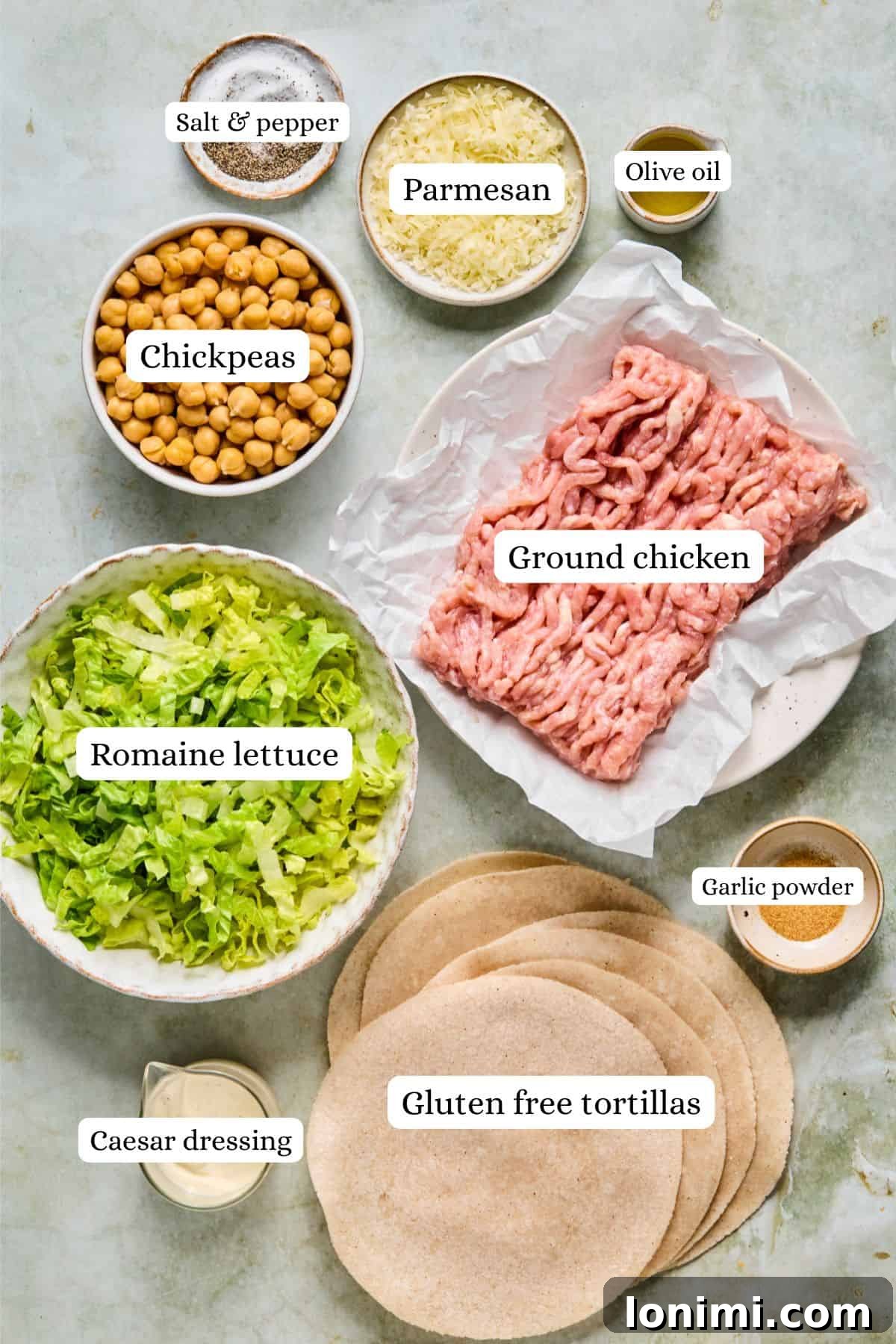 Overhead shot of fresh ingredients for Chicken Caesar Smash Tacos, including crisp romaine, roasted chickpeas, and stack of tortillas