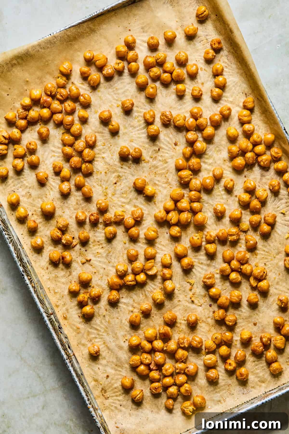 Step 2: Roasted chickpeas freshly tossed with olive oil and seasoning on a baking pan after coming out of the oven.