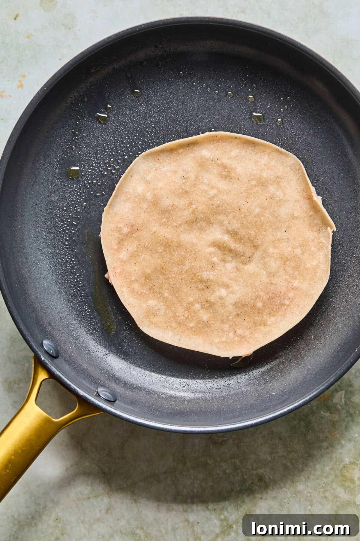 Step 5: The smashed chicken side of a taco searing in a hot skillet, creating a crispy crust.