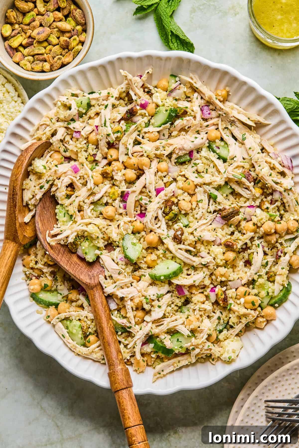 Jennifer Aniston's Go To High Protein Meal Prep Salad 6 step 3: dressing being poured over a tossed quinoa chicken salad