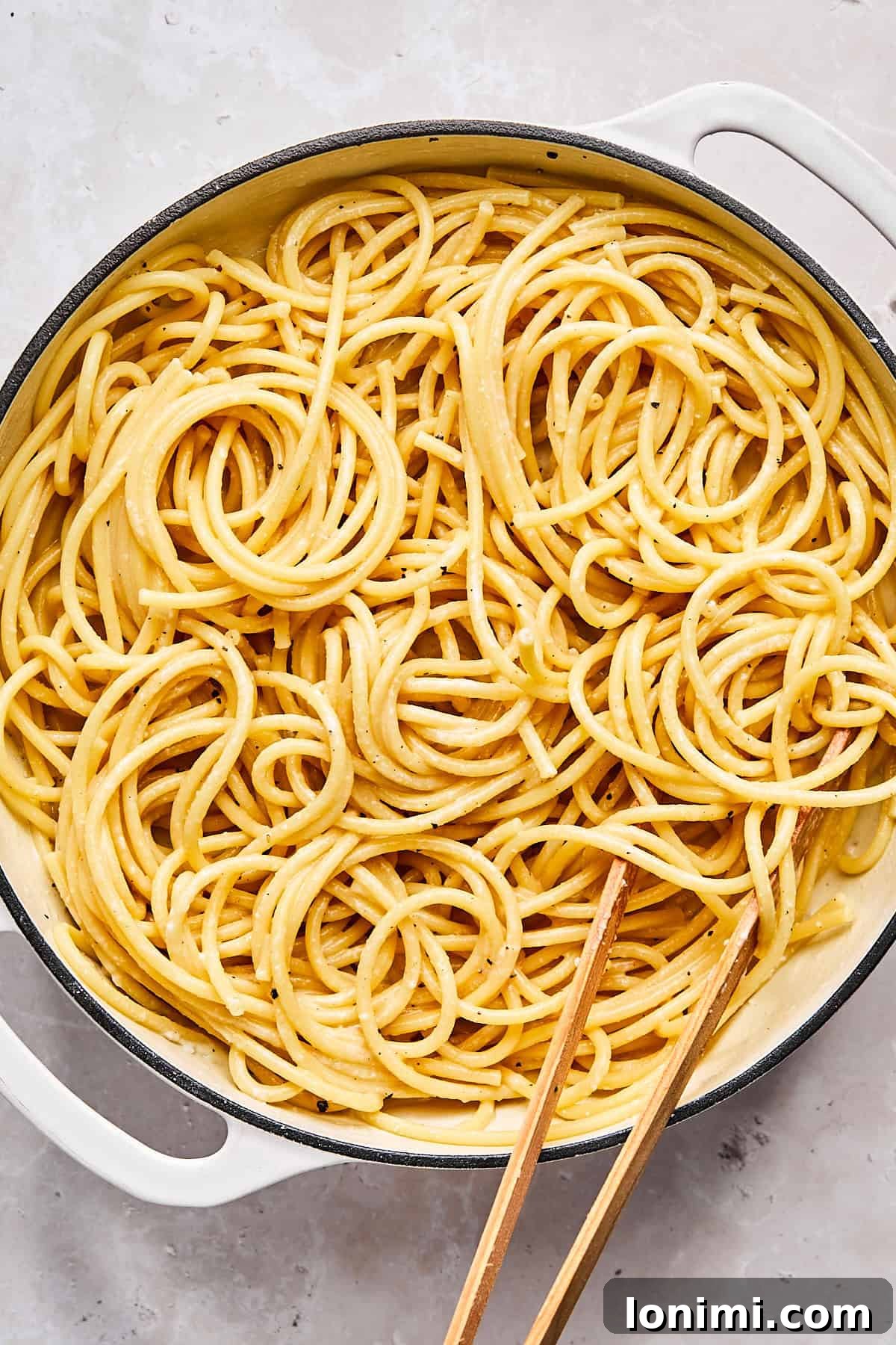 Finished cacio e pepe pasta in skillet with creamy cheese sauce