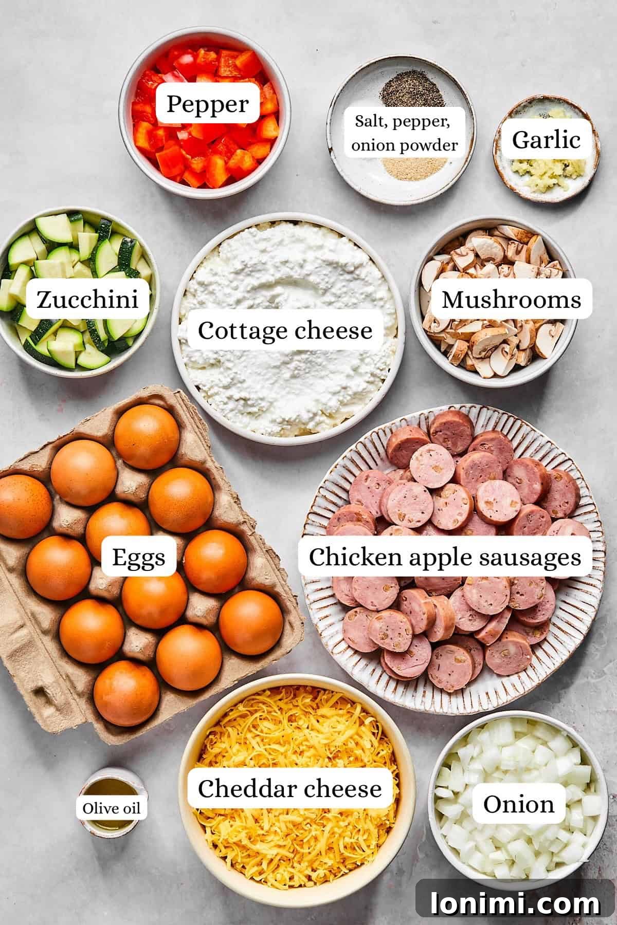 Overhead view of ingredients for cottage cheese egg bake including eggs, sausage, vegetables, and cheese