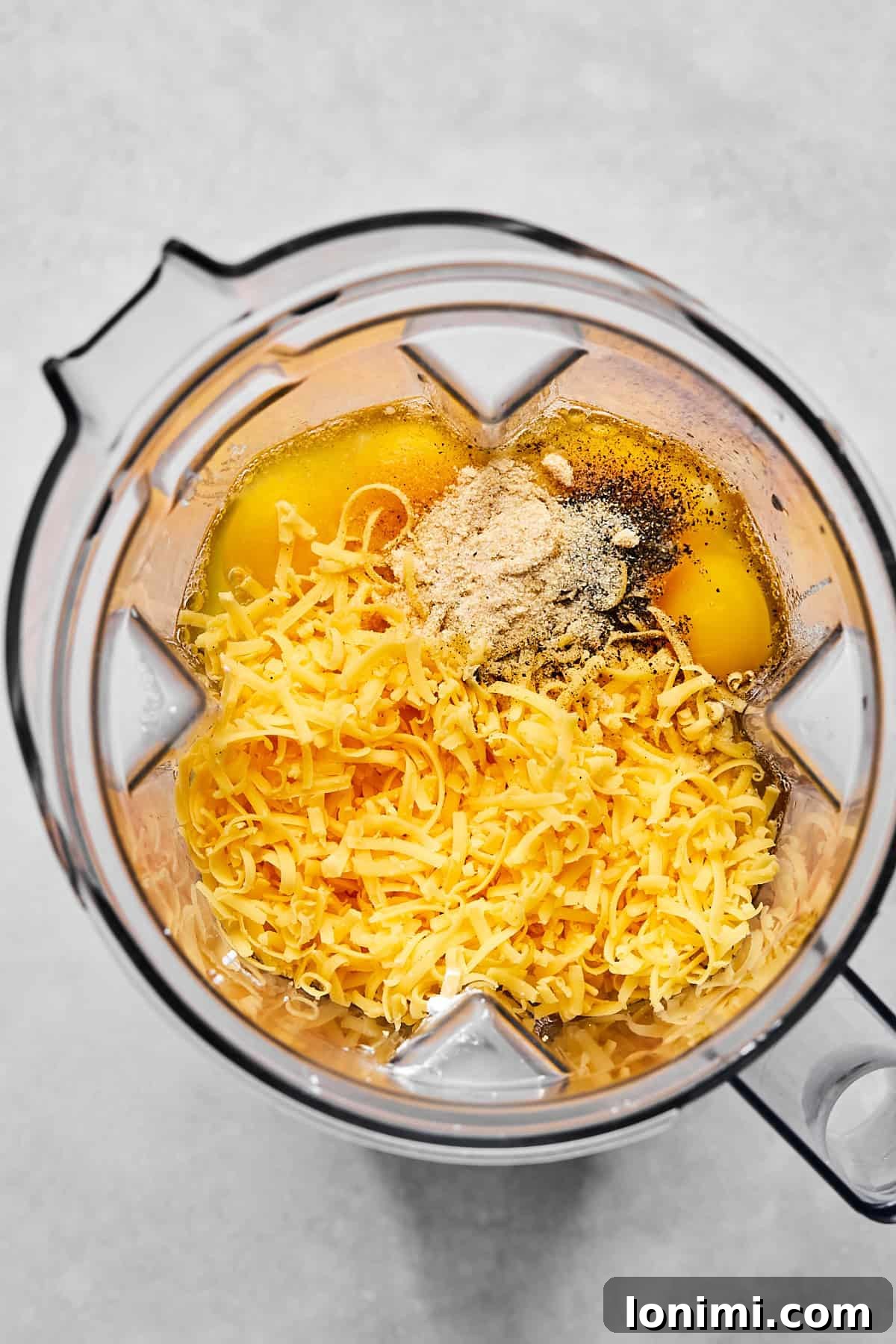 Blender with eggs, cottage cheese, and shredded cheddar ready to be blended