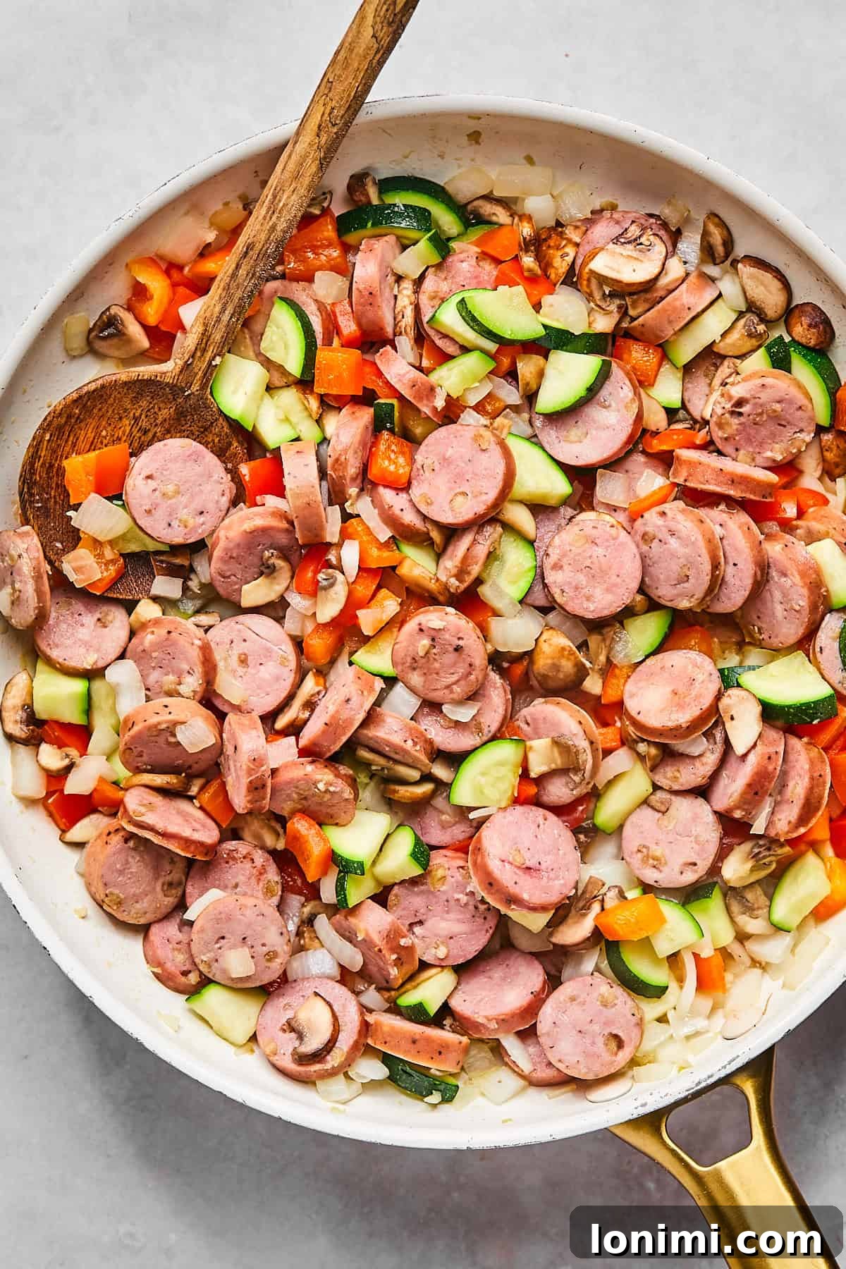 Skillet with browned chicken sausage, diced red pepper, mushrooms, zucchini, and onions