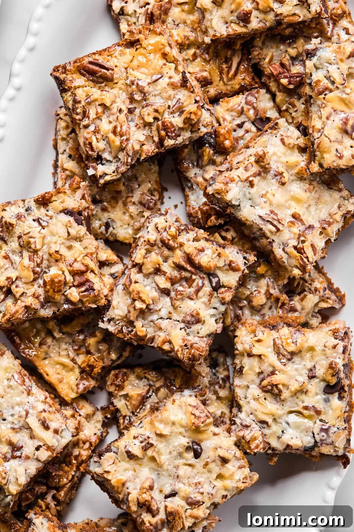 Golden-baked gluten-free magic bars sliced into squares on a wire cooling rack with toasted coconut and chocolate chips visible, highlighting their rich, multi-layered appearance.