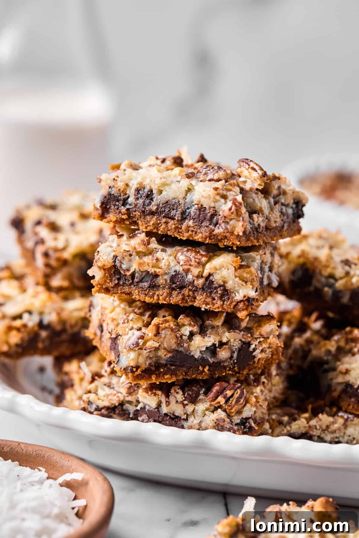 Close-up of a stack of gluten-free magic bar squares showing defined layers of chocolate, coconut, and pecans, highlighting the rich textures.