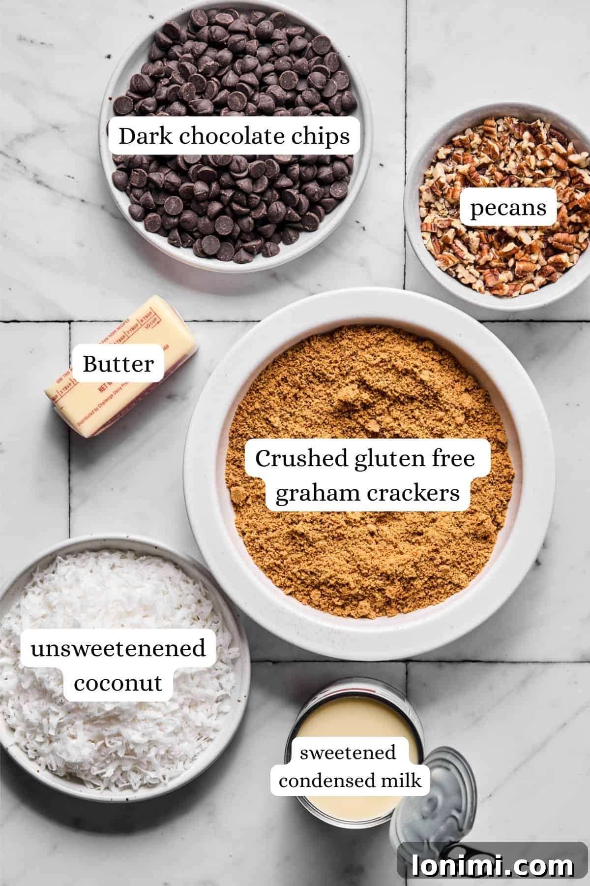 Labeled ingredient lineup for gluten-free magic bars including Sweet Thins crumbs, coconut condensed milk, chocolate chips, and pecans, ready for assembly.
