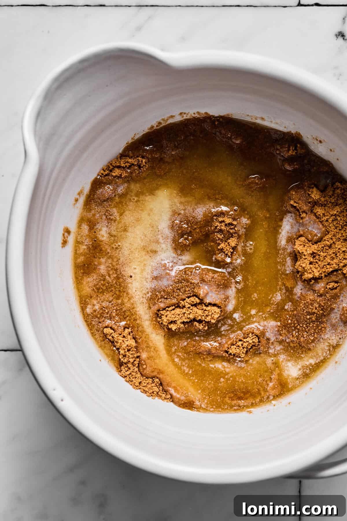 Butter mixed with Sweet Thins crumbs in a bowl before pressing into crust, showing a moist, sandy texture.