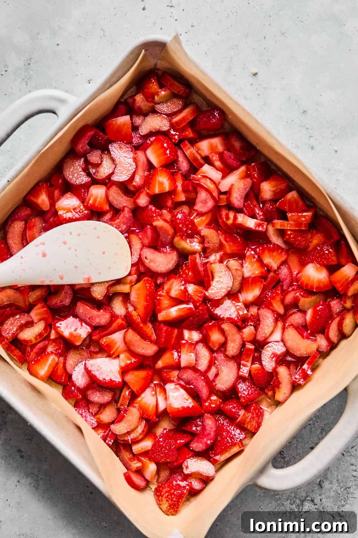 Even layer of strawberry rhubarb fruit filling spread evenly over the pressed crust
