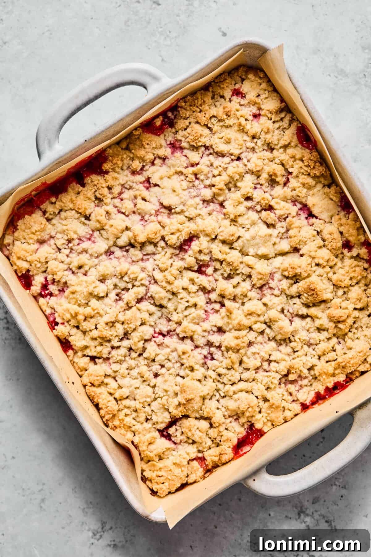Unbaked crumble bars with remaining dough crumbled over the fruit, ready for the oven