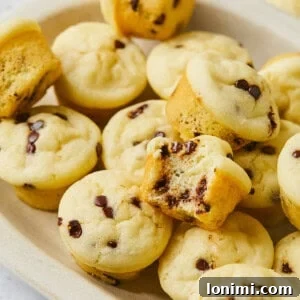 A delightful tray of gluten-free mini muffins, with one cut in half to showcase its fluffy interior, alongside whole muffins.