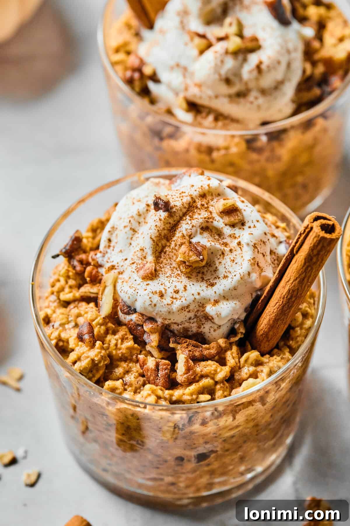 protein pumpkin overnight oats in a glass cup with a cinnamon stick