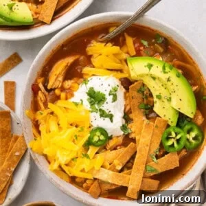 chicken tortilla soup in a bowl with sour cream, avocado and cilantro