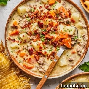 dairy free cheeseburger soup topped with bacon in a bowl with a wooden and metal spoon