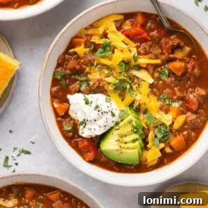 3 bowls of chili with toppings and cornbread on the side