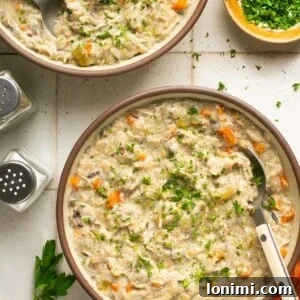 Dairy Free Creamy chicken and wild rice soup in 2 bowls with a red napkin and parsley on the side