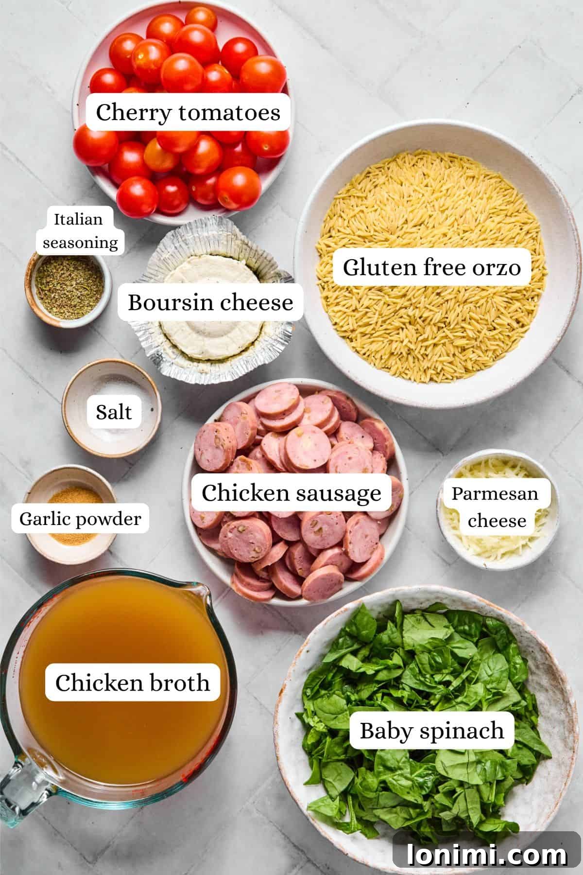 Ingredients for one pan orzo bake including Boursin cheese, gluten-free orzo, chicken sausage, spinach, and cherry tomatoes.