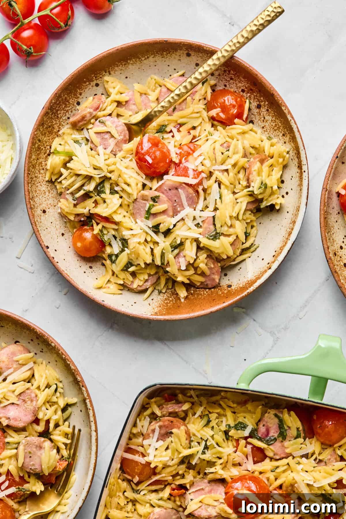 Plate of creamy one pan orzo bake with chicken sausage and spinach, with a spoon lifting a bite from the dish.
