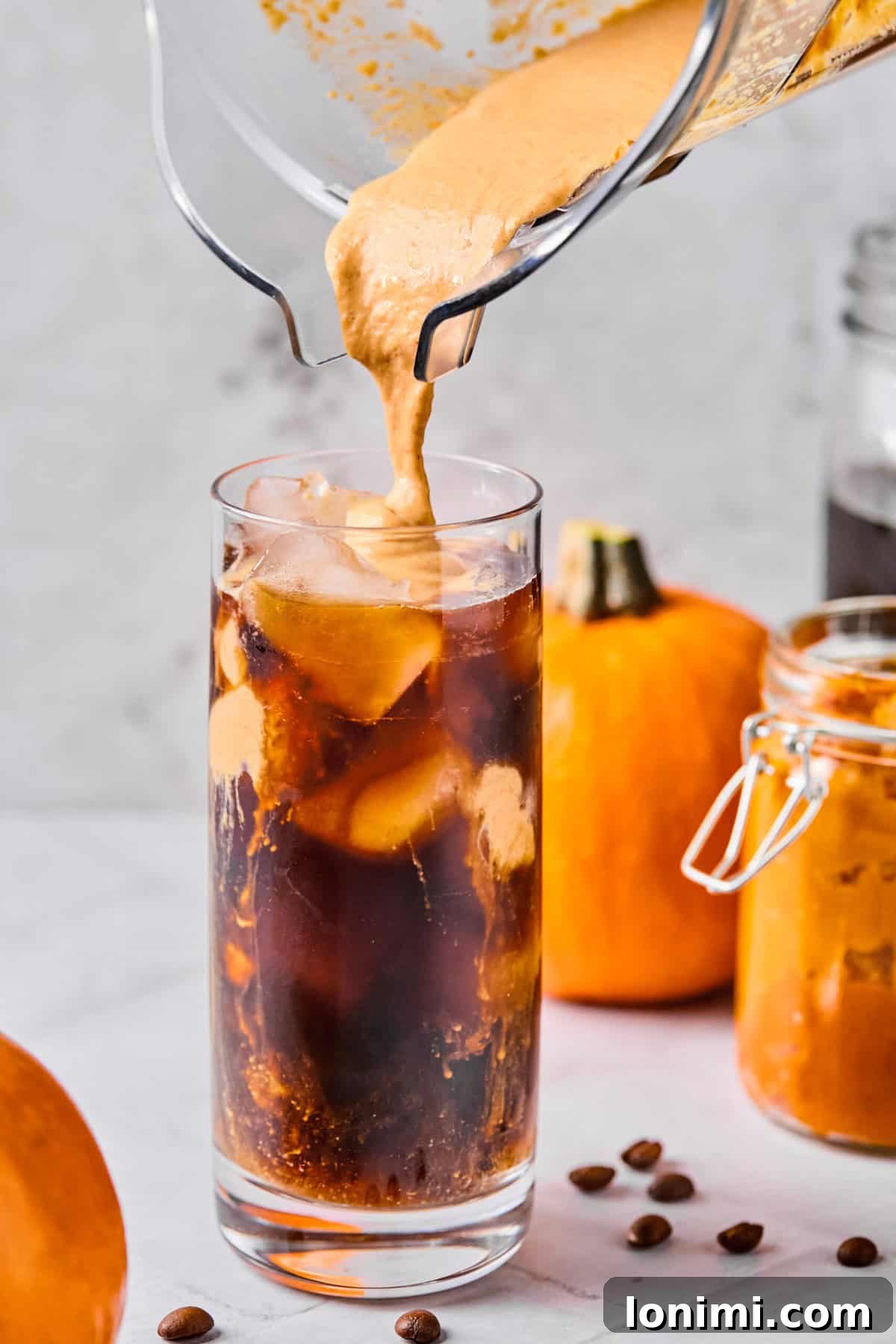 Homemade Protein Pumpkin Cold Foam Perfection 7 The freshly frothed pumpkin protein cold foam being gently spooned or poured over the cold brew coffee, creating a beautiful layered effect.