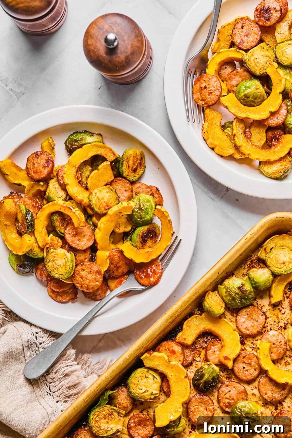 2 plates with a harvest sheet pan dinner, featuring roasted delicata squash, chicken sausage, and Brussels sprouts
