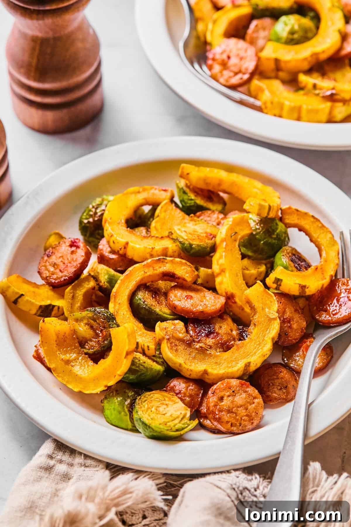 a large plate of harvest sheet pan dinner with perfectly roasted chicken sausage, delicata squash, and Brussels sprouts