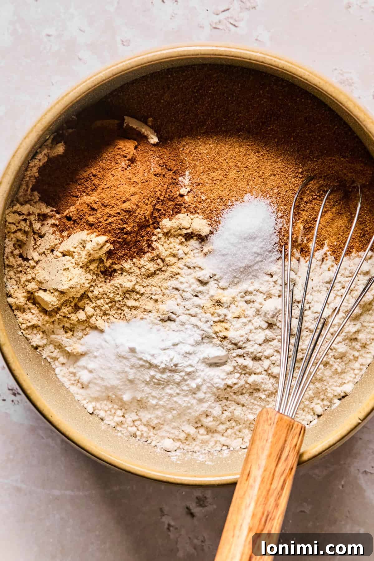 Wholesome Apple Cinnamon Protein Muffins Gluten Free 4 A large mixing bowl filled with the dry ingredients, including gluten-free flour, coconut sugar, vanilla protein powder, cinnamon, baking powder, baking soda, and salt, perfectly prepped for mixing.