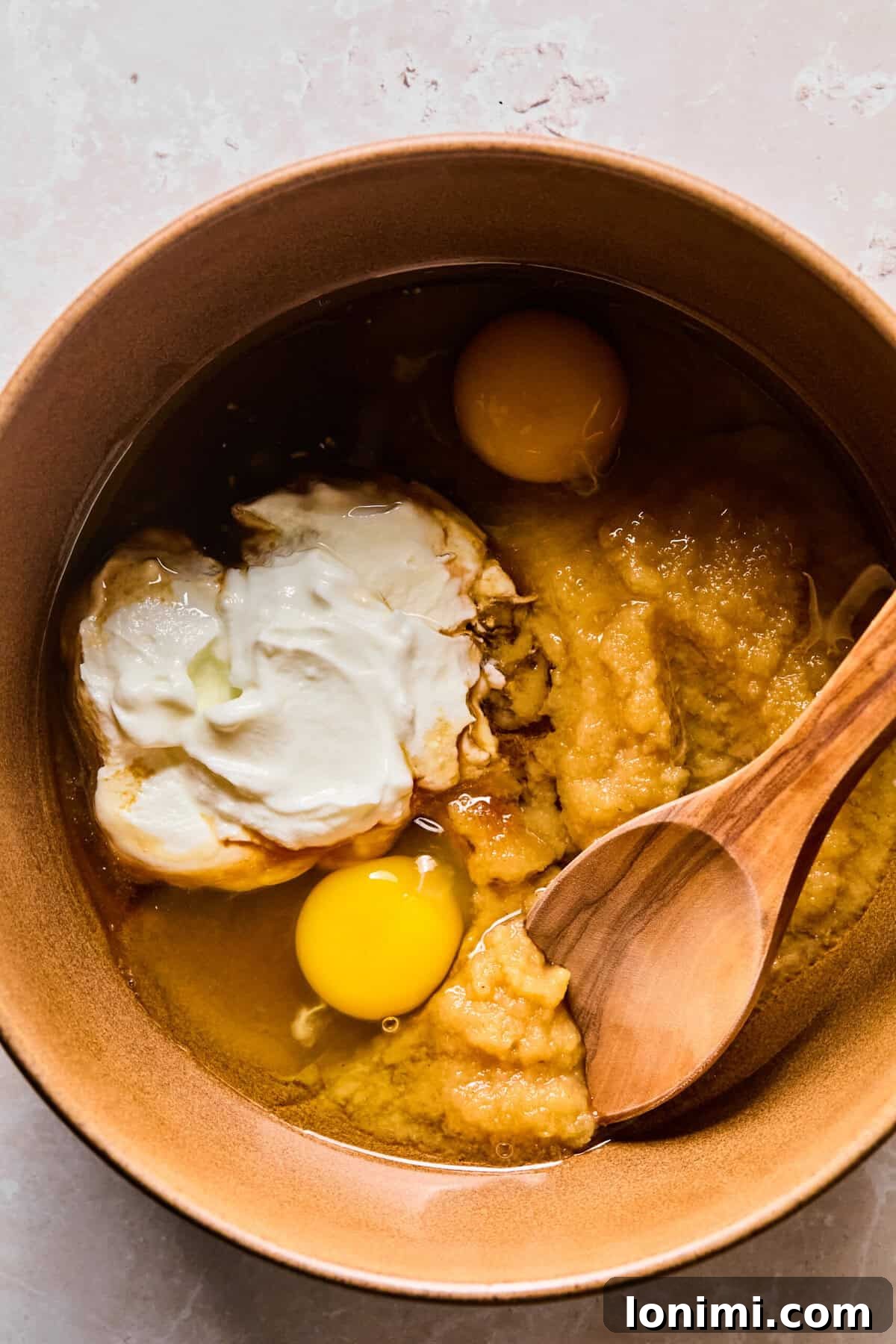 Wholesome Apple Cinnamon Protein Muffins Gluten Free 5 A separate large mixing bowl holds the carefully combined wet ingredients: melted coconut oil, cinnamon applesauce, creamy Greek yogurt, rich maple syrup, fresh eggs, and fragrant vanilla extract.
