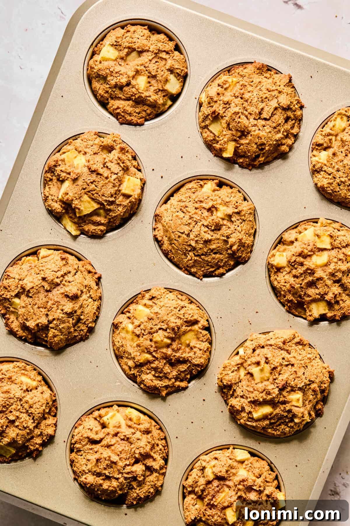 Wholesome Apple Cinnamon Protein Muffins Gluten Free 9 A muffin tin showcasing a batch of freshly baked apple cinnamon protein muffins, each with a perfectly golden and risen top, cooled and ready to enjoy.