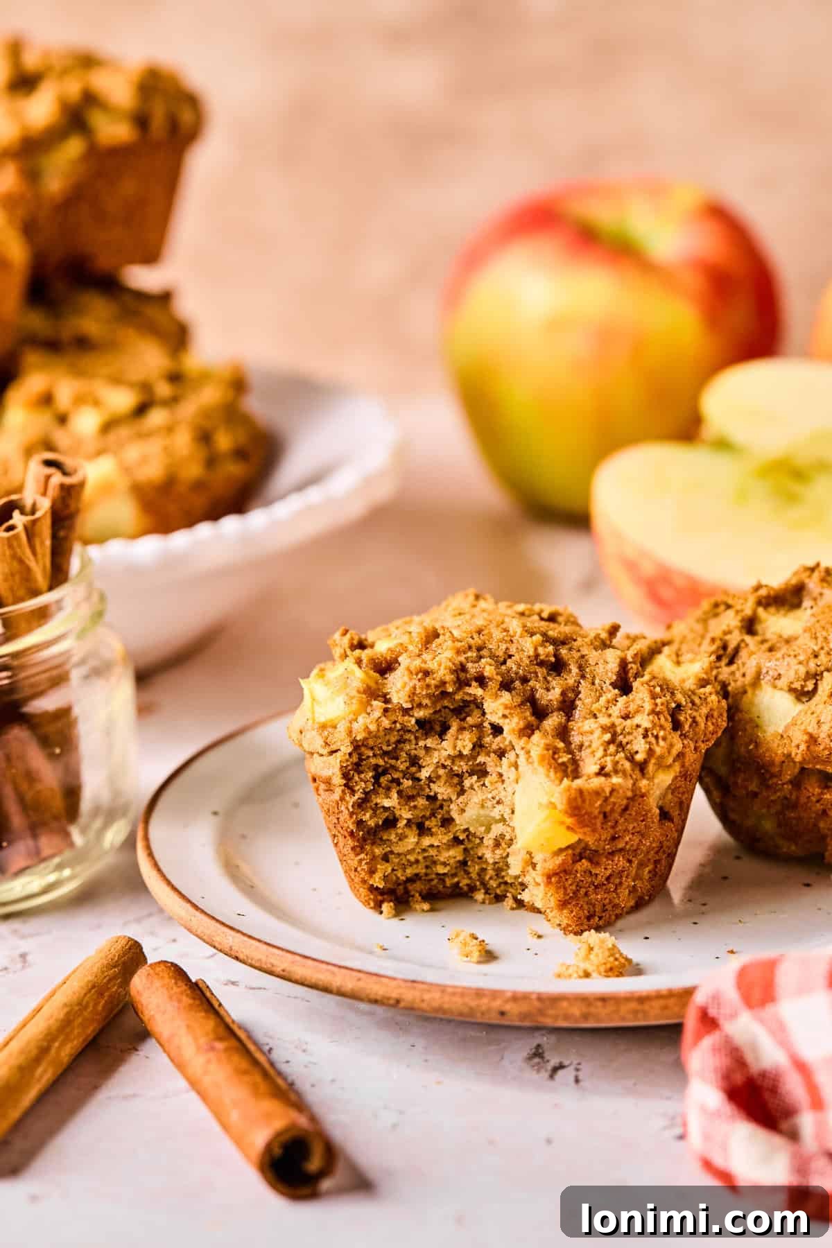 Wholesome Apple Cinnamon Protein Muffins Gluten Free 10 A beautifully baked apple cinnamon protein muffin on a simple white plate, with a delectable bite taken out, revealing its soft, apple-filled interior.