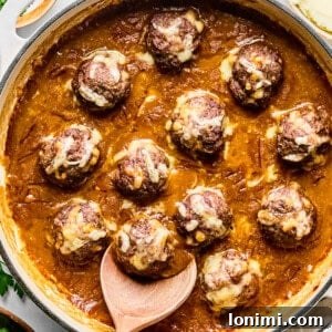 French onion meatballs in a skillet with a wooden spoon