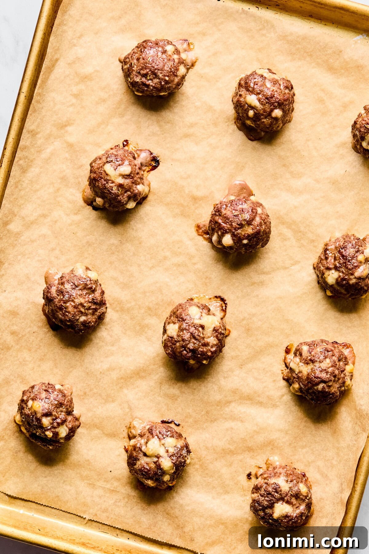 Formed meatballs on a parchment-lined baking sheet, ready for baking.