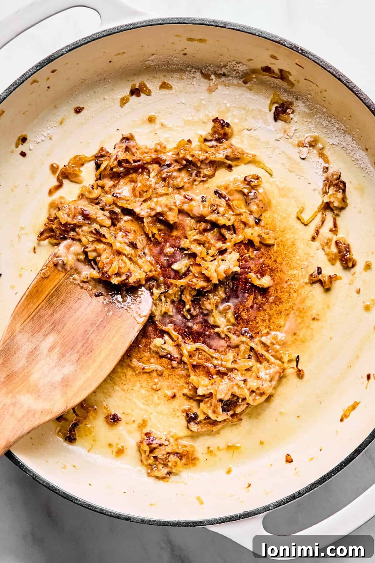 Caramelized onions coated in gluten-free flour in a large oven-safe skillet.