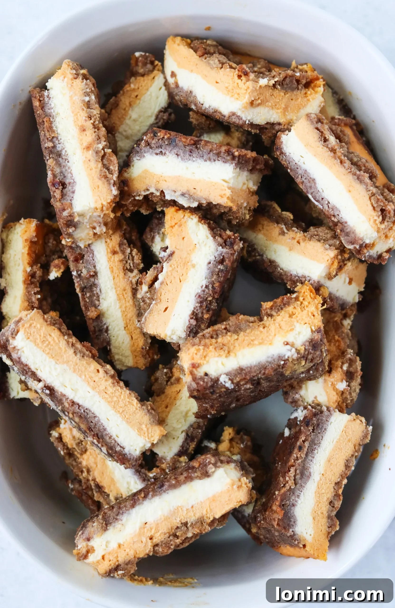 Decadent Grain Free Gluten Free Lactose Free Pumpkin Cheesecake Bars 3 Pumpkin Cheesecake Bars showing the distinct layers of pecan crust and creamy filling