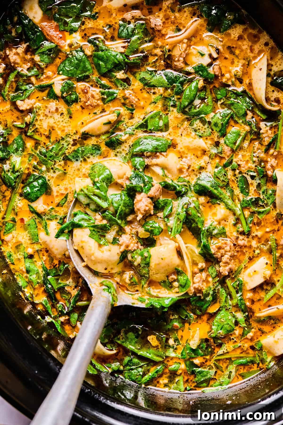 Slow Cooker Creamy Sausage Tortellini Soup 11 the finished italian sausage and tortellini soup in the crockpot with a large silver spoon