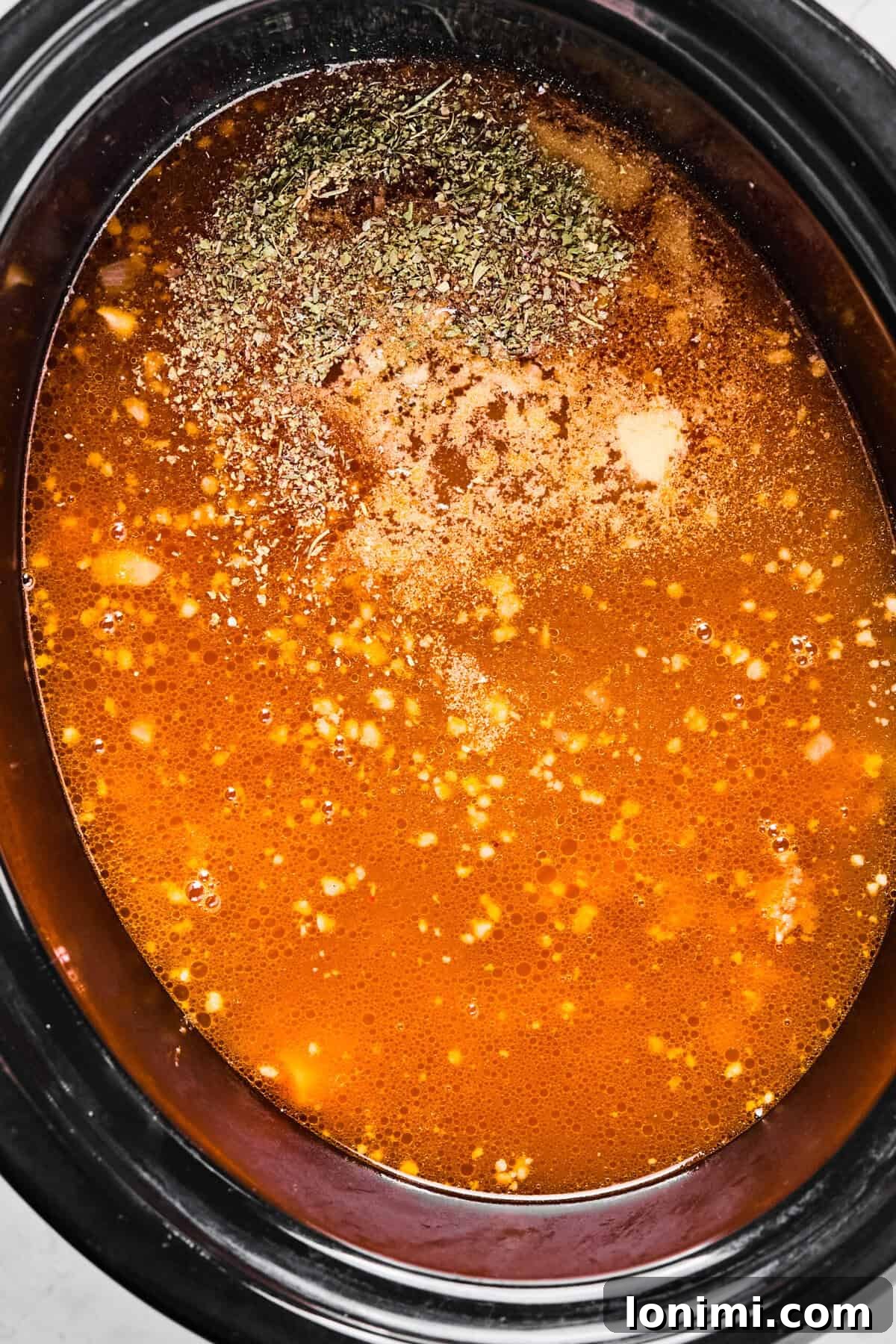Slow Cooker Creamy Sausage Tortellini Soup 7 chicken broth and seasonings covering the sausage and veggies in the crockpot