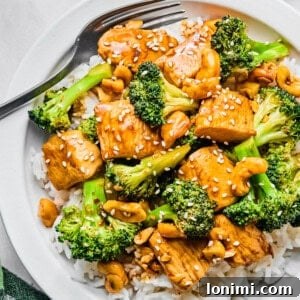 chicken and broccoli stir fry over white rice on a plate with a fork