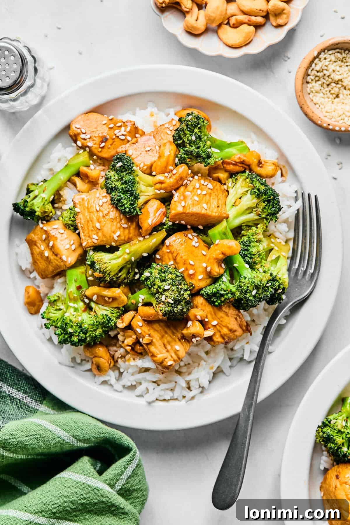 chicken broccoli stir fry over white rice on a white plate