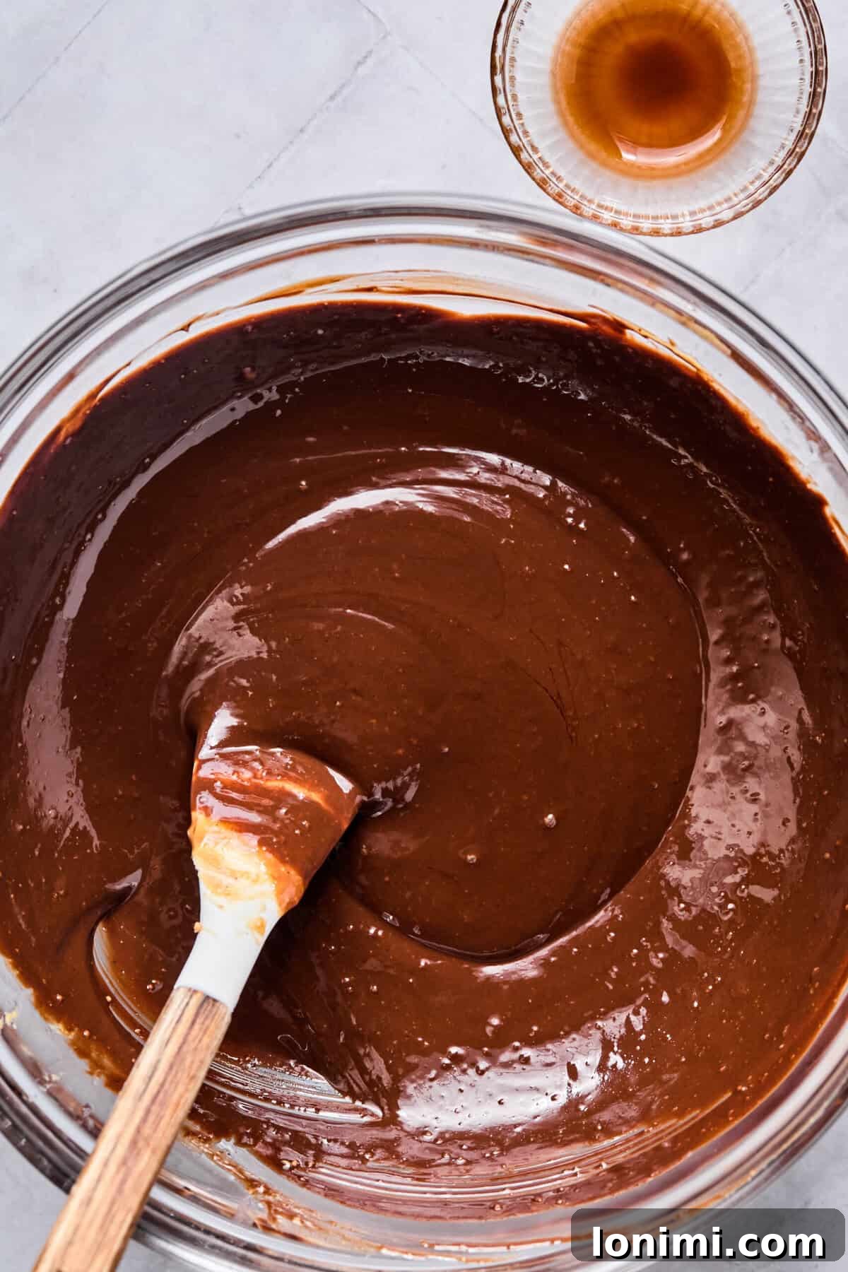 Melted chocolate chips, peanut butter, butter, and vanilla in a glass bowl, stirred until smooth and glistening.