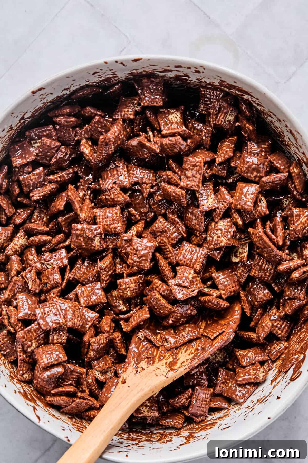 Chex cereal gently tossed in a bowl until each piece is evenly coated with the melted chocolate peanut butter mixture, taking care to avoid breakage.