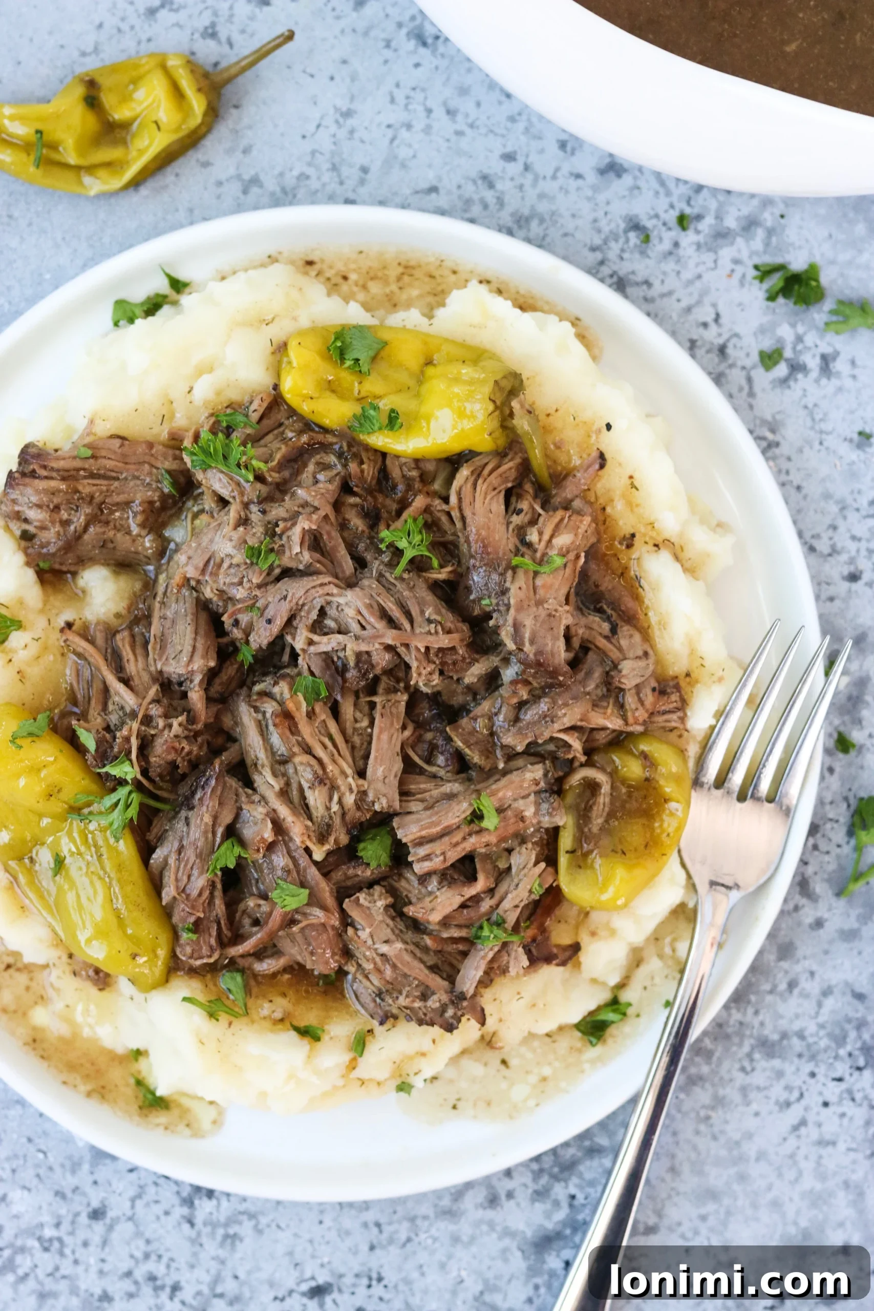Spicy ranch pot roast shredded and placed on top of garlic cauliflower mash, ready to be served