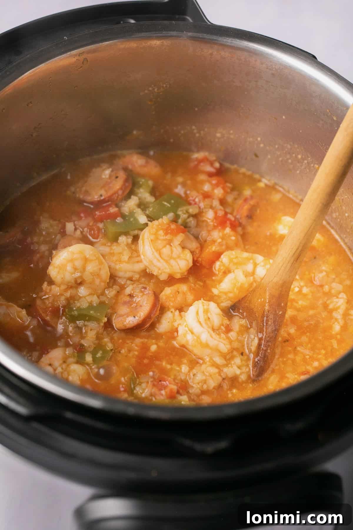 an instant pot filled with shrimp, broth, sausage, and veggies