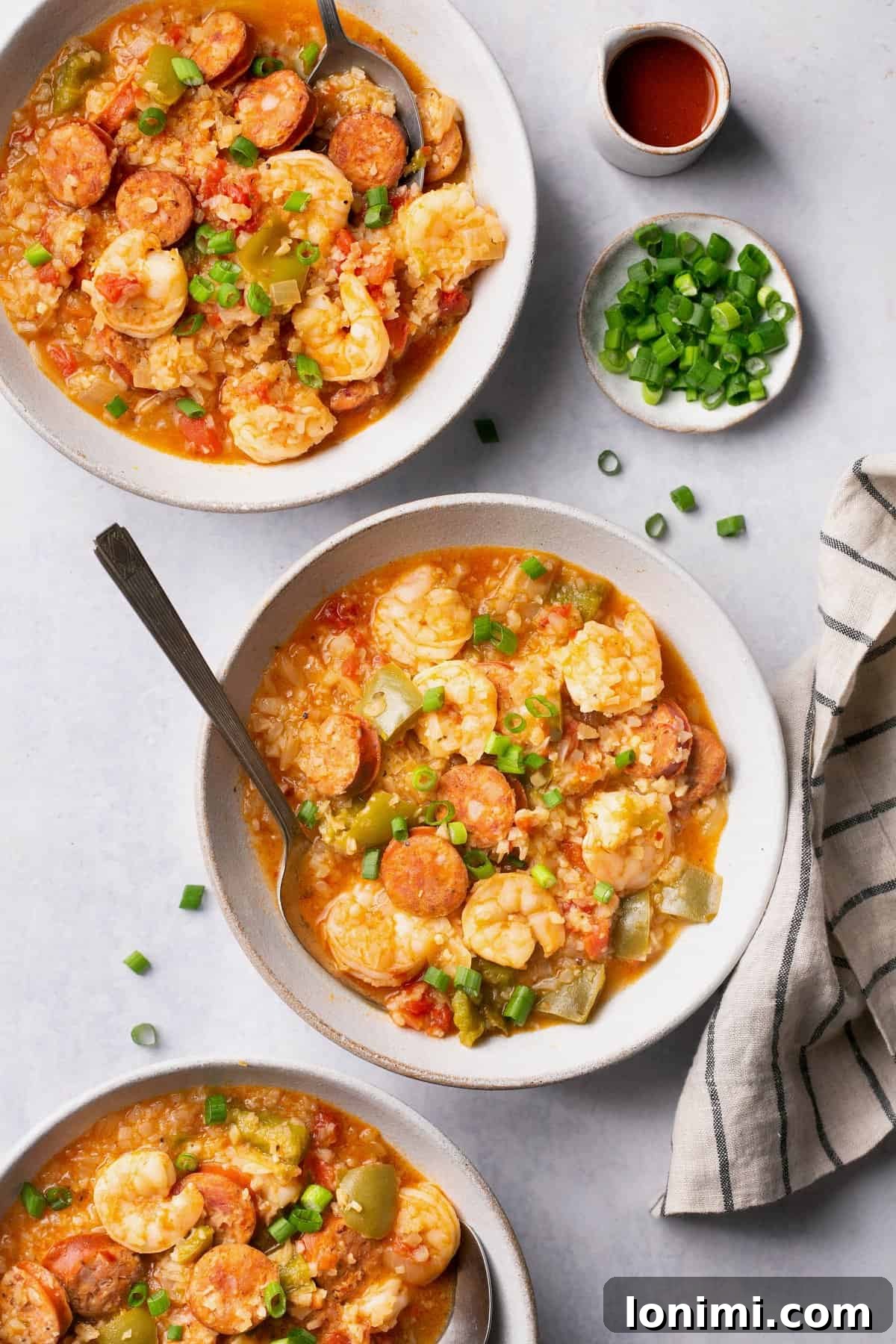 and overhead shot of two bowls of jambalaya soup topped with green onions