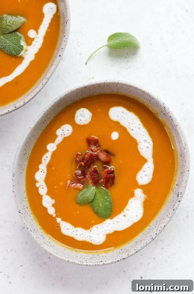 25 Hearty Whole30 Soups, Stews, and Chilis 9 Creamy Butternut Squash Soup topped with crispy bacon and fresh sage, Whole30 and AIP compliant, vibrant orange color.