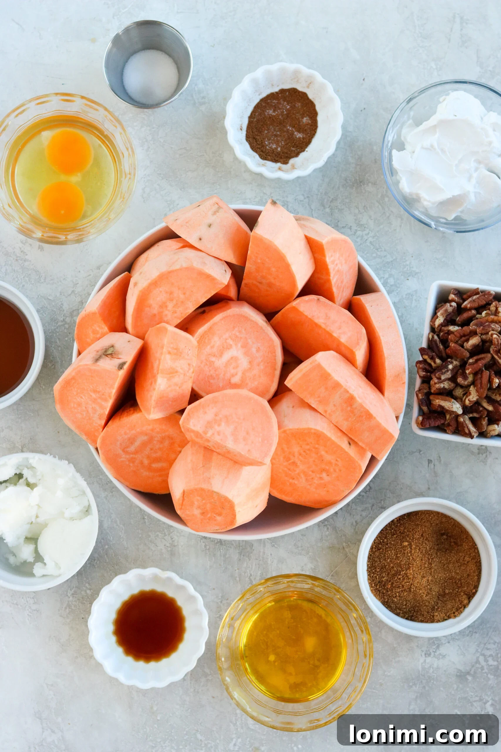A collection of healthy ingredients including raw pecans, coconut milk, and coconut sugar, laid out for a paleo and healthier sweet potato casserole recipe.