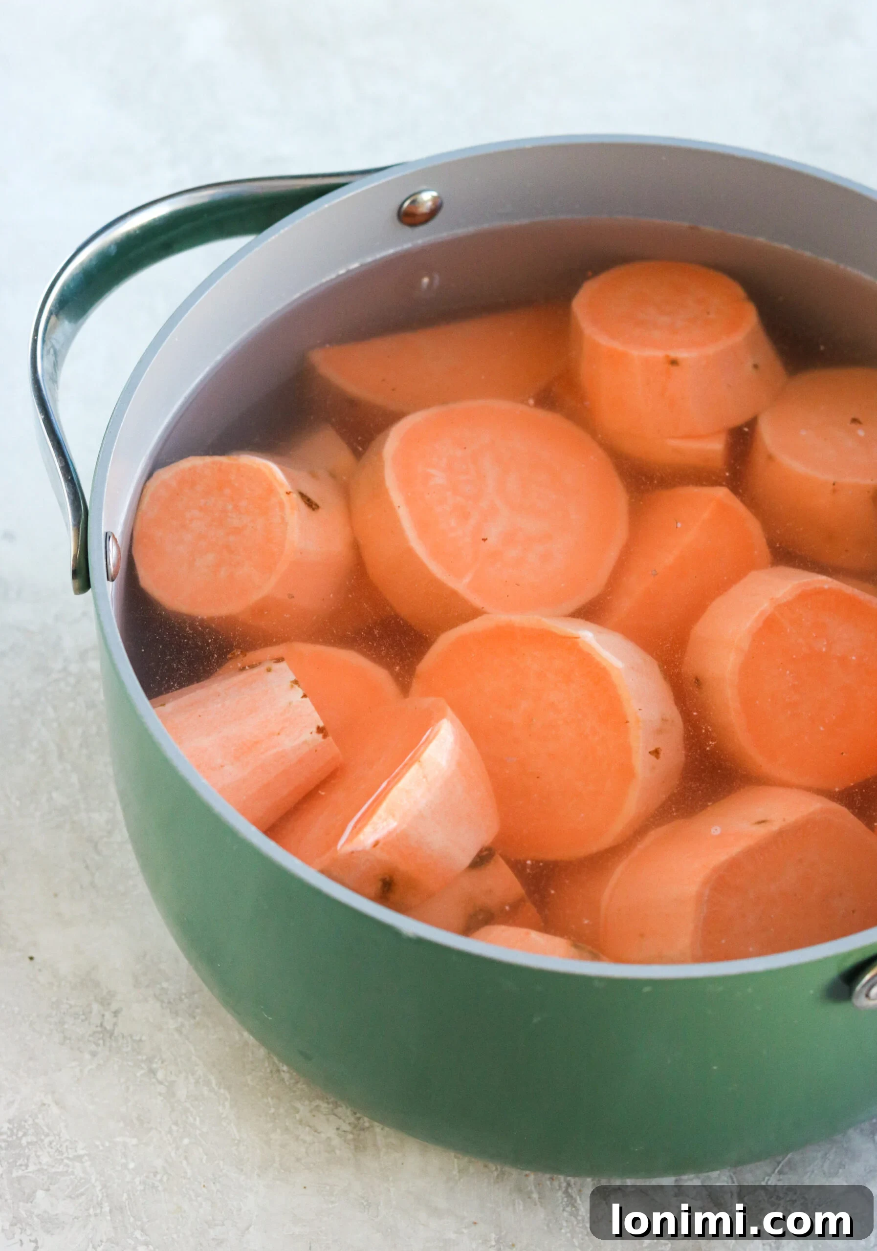 Peeled and cut sweet potatoes boiling in a pot of water, ready for mashing in the sweet potato casserole recipe.
