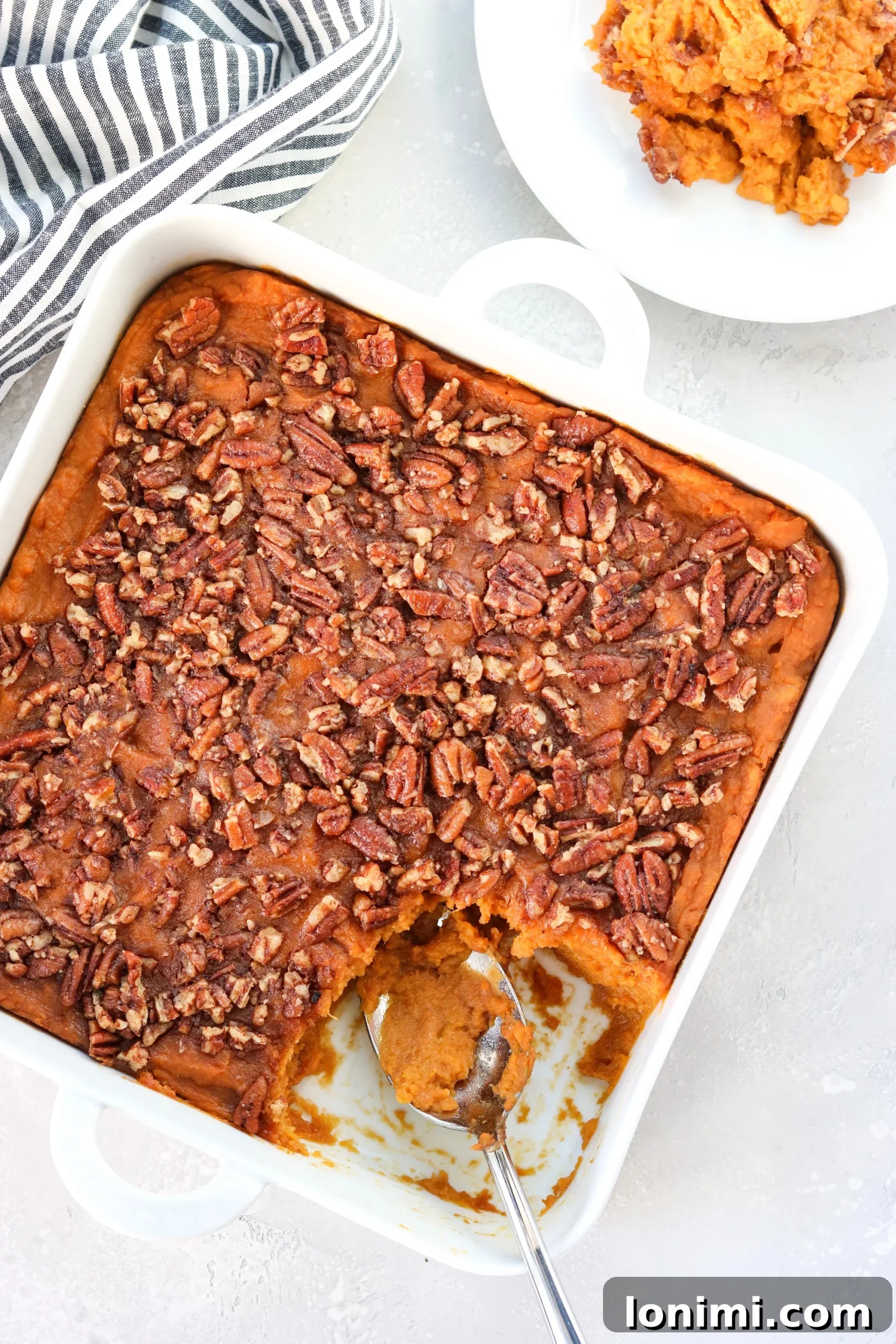 An inviting overhead shot of the perfectly cooked paleo sweet potato casserole, featuring a golden, bubbly pecan topping, ready to be served from a white baking dish.
