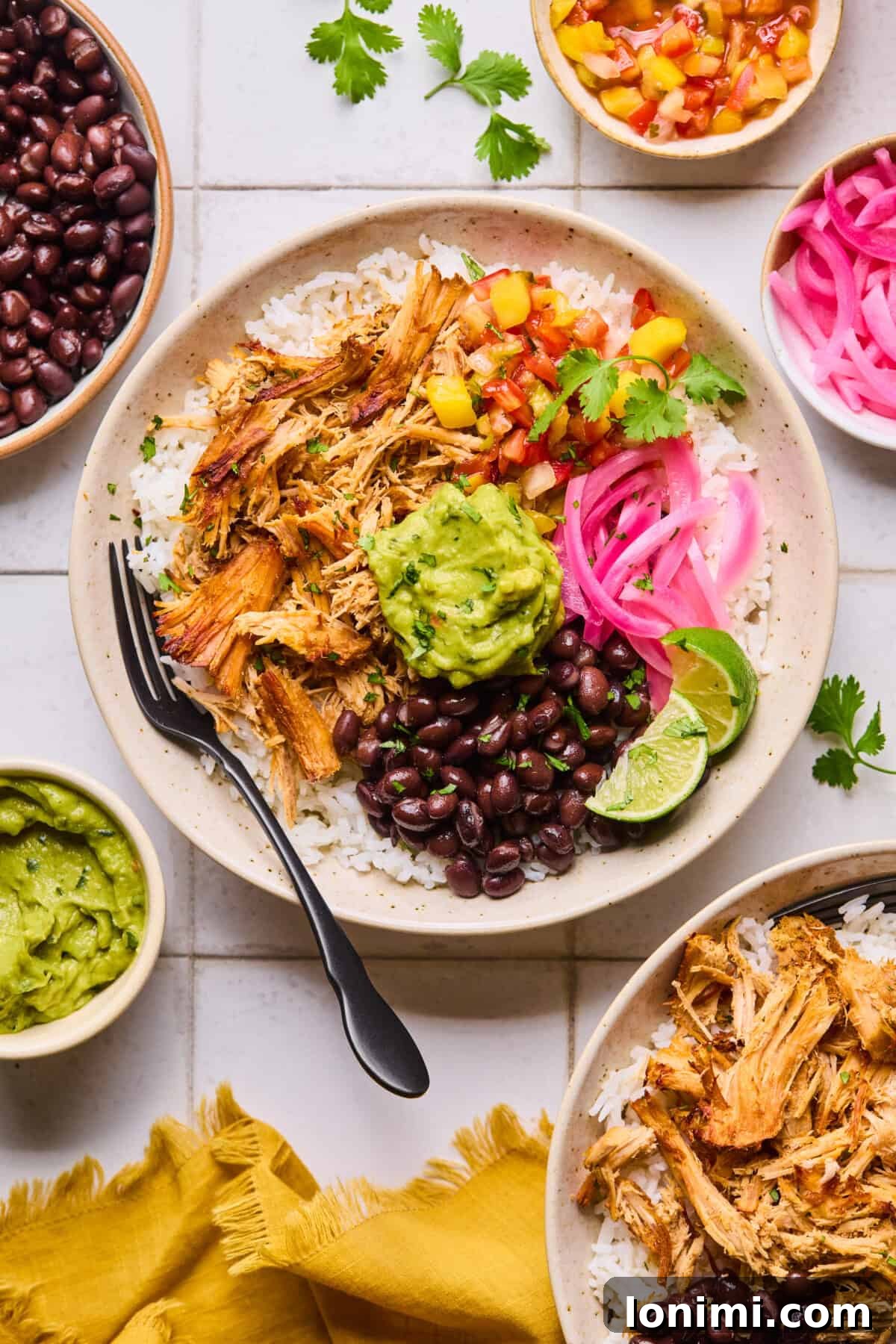 A close-up of juicy slow cooker pork carnitas with crispy edges, served in a rustic bowl, garnished with a lime wedge and vibrant pickled onions.