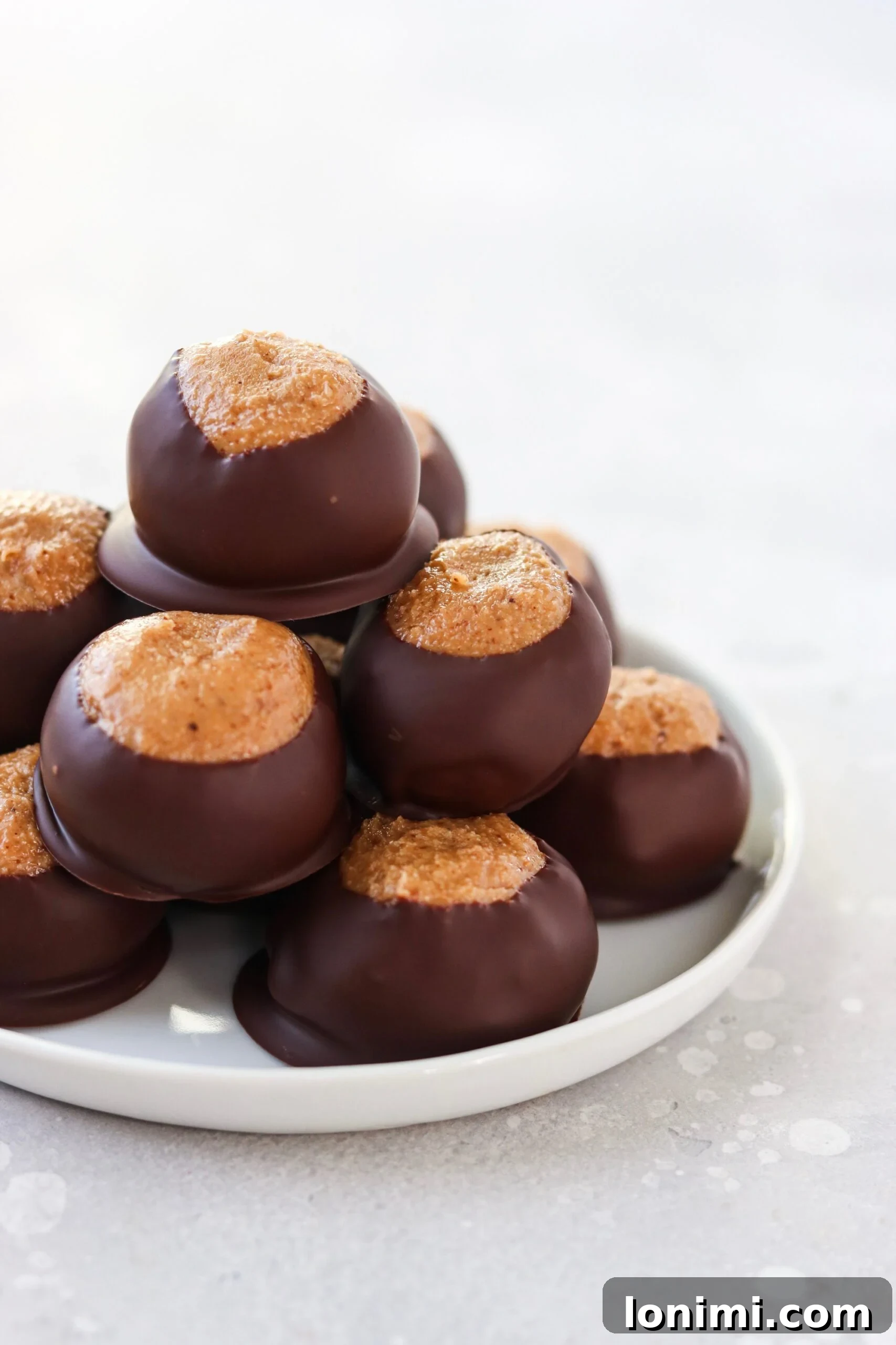 Paleo Buckeye Balls, coated in dark chocolate with a visible nut butter center, perfect for a healthy holiday treat.